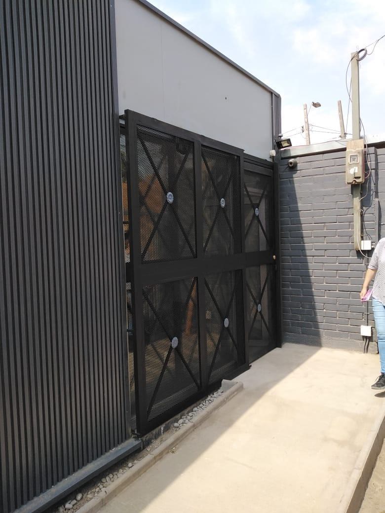 Portón corredero negro con diseño en cruz, fabricado e instalado por HV Metal